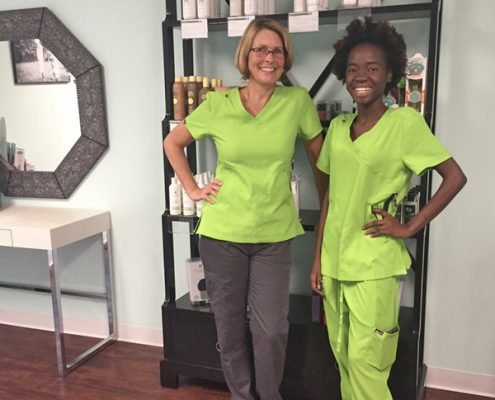 Smiling lice removal technicians wearing bright green scrubs